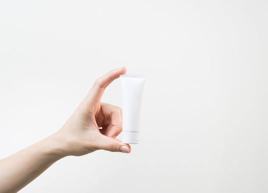 close_up_of_hand_holding_white_lubricant_with_white_background